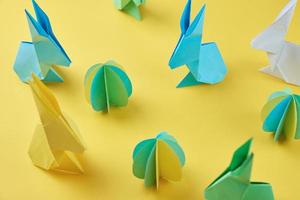 conejos de origami de papel y huevos de colores sobre fondo amarillo foto