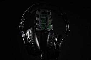 Studio microphone and headphones on black background. Online podcast concept photo