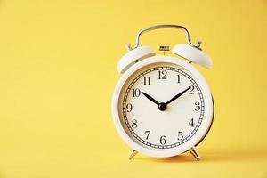 White vintage alarm clock on a yellow background with copy space photo