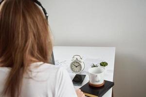 mujer escuchando en línea curso en auriculares, distancia educación foto