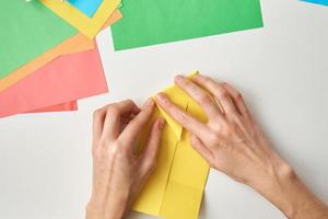 concepto de bricolaje. mujer hace origami conejo de pascua con papel de color. lecciones de origami foto