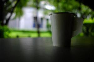 blanco reciclado papel café taza en el mesa en oscuro tono. foto