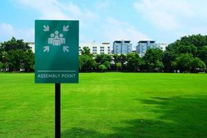 Assembly Point Sign with Green Grass Field Background. photo