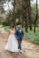 wedding walk of the bride and groom in the deciduous forest in summer photo