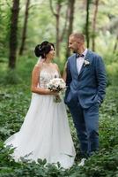 wedding walk of the bride and groom in the deciduous forest in summer photo