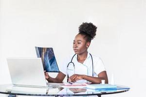 African American Doctor looking shoulder x-ray film in hospital. Radiography concept. radiology female doctor examining x ray film of patient at hospital room. photo