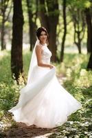 retrato de un elegante novia niña en un camino en un caduco bosque con un ramo de flores foto