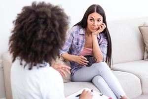 Woman at therapy session. Attentive psychologist. Attentive psychologist holding pencil in her hands making written notes while listening to her client photo