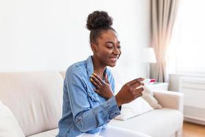 Happy black woman with a pregnancy test on sofa,Young woman looking at pregnance test in happiness happy that she is going to have baby. Finally pregnant. photo