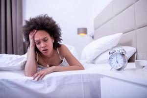 young beautiful woman at home bedroom lying in bed late at night trying to sleep suffering insomnia sleeping disorder or scared on nightmares looking sad worried and stressed photo