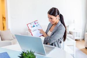 Focused businesswoman presenting charts and graphs on video call online. Young business woman having conference call with client on laptop. Closeup business woman working laptop computer indoor. photo