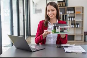 Accountant, businessman, real estate agent, Businessman handing model house to customers along with house interest calculation documents for customers to sign. photo