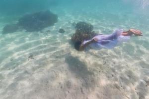 White dressed girl while swiming underwater photo