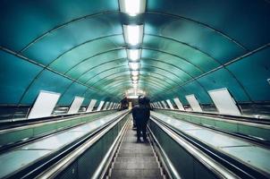 Moving subway staircase with an unknown human silhouette. photo