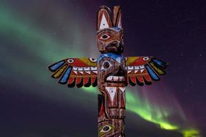 Totem wood pole on green northern lights background photo