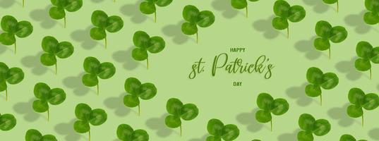 Happy St. Patrick's Day text with clover leaf pattern on colored background. Greeting banner photo