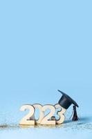 Class of 2023 concept. Wooden number 2023 with graduated cap on colored background photo