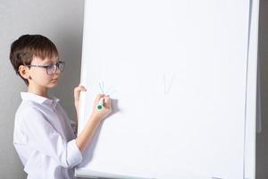 European white boy standing near school board for presentation. Education, childhood, homework and school concept. photo