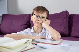 joven chico leyendo libro a hogar. educación, infancia, deberes y colegio concepto. foto