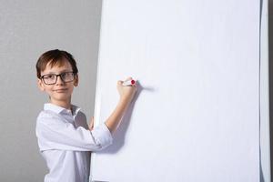 europeo blanco chico en pie cerca colegio tablero para presentación. educación, infancia, deberes y colegio concepto. foto