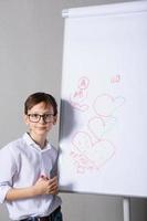 European white boy standing near school board for presentation. Education, childhood, homework and school concept. photo