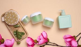 Plastic green cosmetic jars, stone massager, and wooden brush. Beauty treatment tools photo