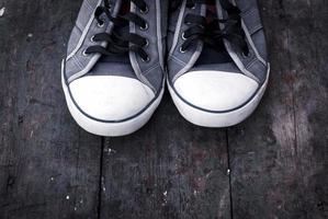 old man's worn sneakers on a wooden surface photo