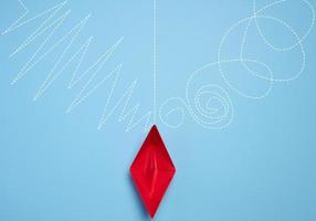 A red paper boat stands in front of different paths, the concept of finding the optimal route, top view photo