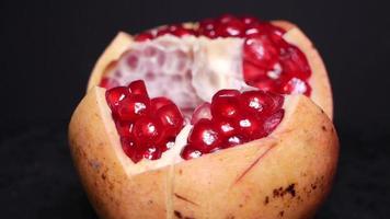 Ripe pomegranate filmed on video against a black background