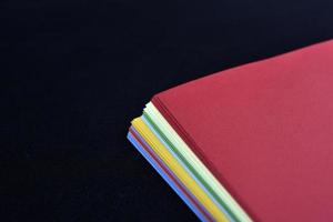 Multicolored sheets of paper on a black background. Colored office paper. A pack of colored paper. photo