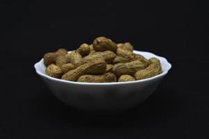 Groundnut. Unpeeled peanuts in a white plate. Peanuts in the peel. photo