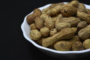 Groundnut. Unpeeled peanuts in a white plate. Peanuts in the peel. photo