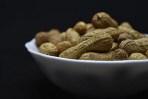 Groundnut. Unpeeled peanuts in a white plate. Peanuts in the peel. photo