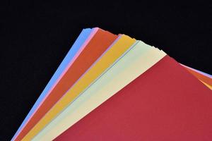 Multicolored sheets of paper on a black background. Colored office paper. A pack of colored paper. photo