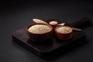 Wholesome raw quinoa in a bowl on a dark concrete background photo