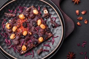 Handmade chocolate with berries, nuts and spices on a dark background photo