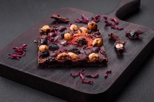 Handmade chocolate with berries, nuts and spices on a dark background photo