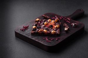 Handmade chocolate with berries, nuts and spices on a dark background photo