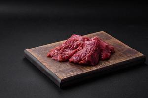 Raw beef cut into several pieces on a wooden cutting board photo