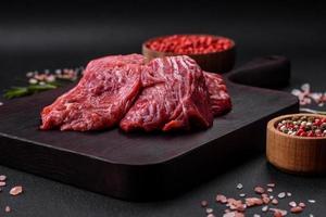 Raw beef cut into several pieces on a wooden cutting board photo