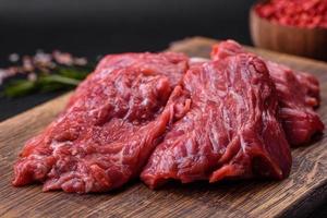 Raw beef cut into several pieces on a wooden cutting board photo