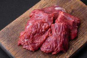 Raw beef cut into several pieces on a wooden cutting board photo