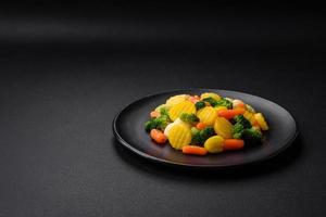 Delicious fresh vegetables steamed carrots, broccoli, cauliflower on a black plate photo