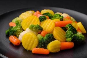 Delicious fresh vegetables steamed carrots, broccoli, cauliflower on a black plate photo