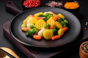 Delicious fresh vegetables steamed carrots, broccoli, cauliflower on a black plate photo