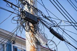 los cables eléctricos se enredan en un poste de madera foto