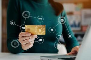 Woman using smart phone for mobile payments online shopping,omni channel,sitting on table,virtual icons graphics interface screen in morning light photo