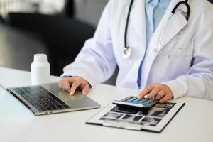 Medical technology concept. Doctor working with mobile phone and stethoscope and digital tablet laptop in modern office at hospital photo