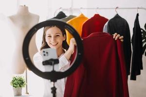 Moda blogger concepto, joven mujer de venta ropa en vídeo streaming.startup pequeño negocio pequeño, utilizando teléfono inteligente o tableta tomando recibir y comprobación en estudio foto