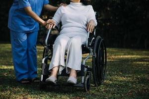 asiático joven cuidador enfermero apoyo mayor más viejo masculino caminando al aire libre. especialista niña médico ayuda y tomar cuidado de mayor maduro hombre paciente haciendo físico terapia en público parque a enfermería hogar. foto